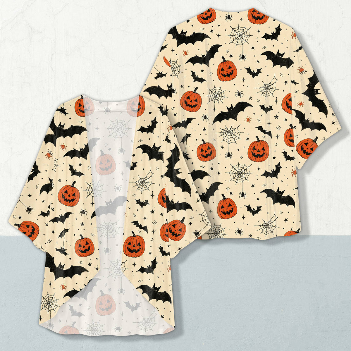 Halloween cardigan featuring black bats and orange pumpkins on a light beige background, front view