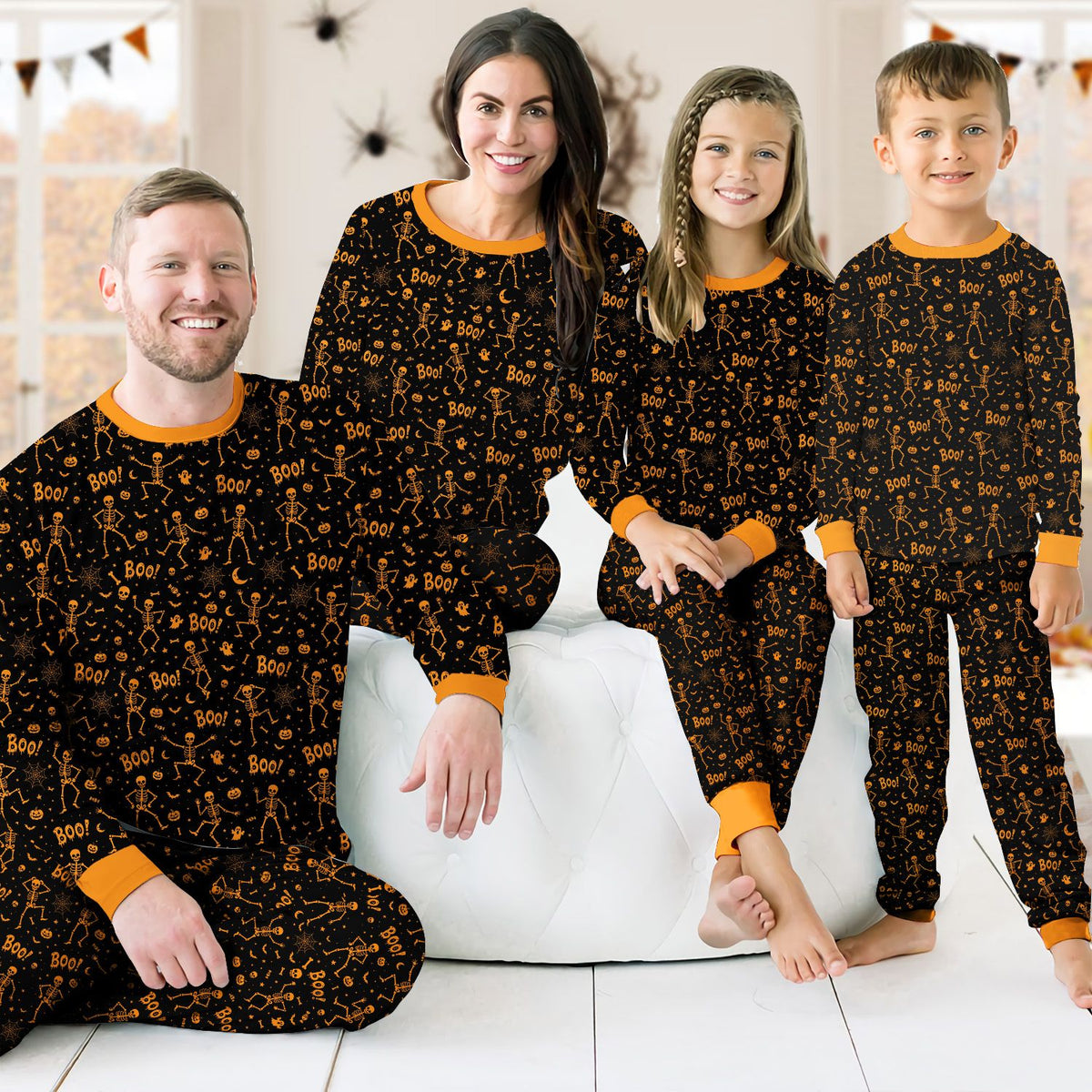 Lifestyle view of a family wearing matching holiday pajamas featuring skeletons and ghosts