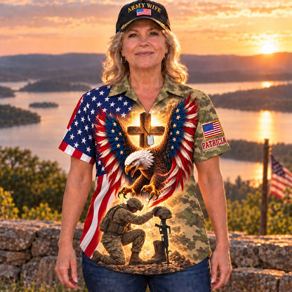 Woman in an Army Wife cap wearing the personalized camo eagle and cross Hawaiian shirt at a lakeside sunset, front view