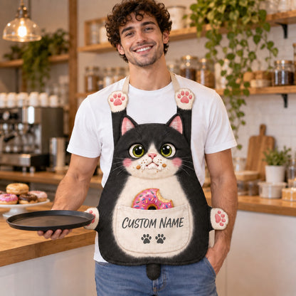 Personalized cat apron with custom name on the pocket, black tuxedo cat, Donut Thief design: a guilty cat with crumbs on its mouth and a half-eaten pink donut in the pocket