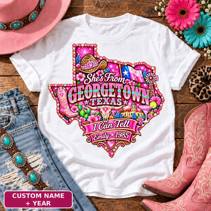 Personalized She's From Georgetown Texas I Can Tell t-shirt on White, custom name and year badge, pink glitter Texas with rhinestone border, leopard cowgirl hat, flag, boots, longhorn and custom name and year banner NEW2